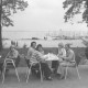 ARH Slg. Bartling 1217, Nordufer, Blick auf eine Gruppe von Gästen auf der Terrasse des Restaurants Weisse Düne, dahinter der Uferweg, der leere Badestrand und der See mit Bootssteg (rechts), Steinhuder Meer