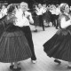 Stadtarchiv Neustadt a. Rbge., ARH Slg. Bartling 1889, Seniorinnen beim Tanz auf Straßenpflaster mit Frauen einer Trachtengruppe, Neustadt a. Rbge.