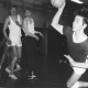 Stadtarchiv Neustadt a. Rbge., ARH Slg. Bartling 1963, Jugend-Handballer in der TSV-Sporthalle beim Fallwurf auf das Tor, links im Hintergrund drei beobachtende Mitspieler, Blick von der Torlinie, Neustadt a. Rbge.