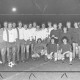 Stadtarchiv Neustadt a. Rbge., ARH Slg. Bartling 1989, Zwei Fußballmannschaften vor dem Anstoß am Mittelkreis nebeneinander aufgereiht und stehend, am Abend im Flutlicht, Blick von vorn