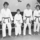 Stadtarchiv Neustadt a. Rbge., ARH Slg. Bartling 2054, Gruppenporträt von vier jugendlichen Karateka im Karate-Gi in einem Übungsraum mit bemalter Wand