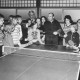 Stadtarchiv Neustadt a. Rbge., ARH Slg. Bartling 2078, Tischtennis-Lehrstunde für Kinder und Jugendliche, die sich rund um eine Tischtennisplatte aufgestellt haben, in einer Sporthalle (in der Mitte der Trainer), Bordenau