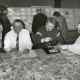 ARH Slg. Bartling 2259, Drei Philatelisten (l. Heinrich Schöneberg-Schnappka) an einem Tisch sitzend, daneben ein junger Briefmarkenfreund, die auf dem Tisch ausgebreitete Schnittmarken sortieren, im Hintergrund die aufgestellten Ausstellungswände mit Exponaten, Neustadt a. Rbg.