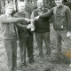 Stadtarchiv Neustadt a. Rbge., ARH Slg. Bartling 2486, Vier Männer nebeneinander auf einer Waldlichtung stehend und auf einen Pokal zeigend, Kreisjägerschaft