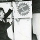 ARH Slg. Bartling 2517, Elektro-Händler Ulrich Pallak kniet links neben einem Kühlschrank der Firma Linde und zeigt auf ein am Kühlschrank befestigtes Werbeschild mit der Aufschrift "Linde, 1. Preis", Neustadt a. Rbge.