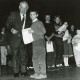 ARH Slg. Bartling 2891, Zahlreiche Grundschulkinder auf einer Bühne stehend mit einer Urkunde in der Hand, vorne Bürgermeister Henry Hahn mit einem Kind in die Kamera schauend, Neustadt a. Rbge.