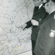 ARH Slg. Bartling 3366, Polizeihauptkommissar Strasser (l.) und Polizeihauptmeister Wittig beim Studium einer an der Wand hängenden topografischen Karte von Neustadt mit Eintragung der Unfallschwerpunkte, Neustadt a. Rbge.