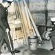 ARH Slg. Bartling 3448, Durchsuchung eines Stallanbaus mit Fachwerkmauer, zwei Polizisten begutachten abgestellte Autoreifen, Buchtal-Fliesen, T-Träger, eine Tonne mit Kleber, eine Bohrmaschine und eine Kabelrolle, Empede