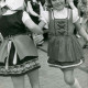 Stadtarchiv Neustadt a. Rbge., ARH Slg. Bartling 360, Erntefest in Stöckendrebber, zwei kleine Mädchen in Trachtenkleidung mit Mütze beim Volkstanz
