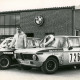 ARH Slg. Bartling 3871, Manfred Mineif, Rennfahrer aus Bordenau, vor einer Werkstatt mit BMW-Logo über der Eingangstür und zwischen zwei für den Motorsport getunten BMW 1800, auf der Motorhaube des ersten ein Siegerkranz, auf der des zweiten ein Pokal, Bordenau