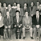 ARH Slg. Bartling 4133, Gruppenfoto der Gemeinderatsmitglieder (?), 13 Männer und 1 Frau, sitzend und stehend vor einem Bühnenvorhang, Empede