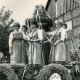 Stadtarchiv Neustadt a. Rbge., ARH Slg. Bartling 4154, Junge Frauen im Dirndlkleid auf einem geschmückten Wagen die Erntekrone haltend beim Erntefestumzug, im Hintergrund ein Fachwerkgiebel, Empede