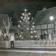 ARH Slg. Bartling 4527, Mit einem festlich beleuchteten Tannenbaum bestandener Aloys-Bunge-Platz in abendlichem Dunkel, Blick von der Straße, Mardorf