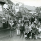 Stadtarchiv Neustadt a. Rbge., ARH Slg. Bartling 4717, Vor zwei geschmückten Wagen nebeneinander stehend die Kinder mit Käfer-Kopfschmuck beim Erntefestumzug, Nöpke
