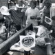 ARH Slg. Bartling 4719, Mädchen beim Nageln an einem Nagelbalken beim Erntefest unter den Augen von zahlreichen anderen Kindern und eines Mannes, der Fähnchen mit der Aufschrift "Milchland Niedersachsen" verteilt, Nöpke