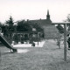 ARH Slg. Bartling 4743, Blick über die Spielgeräte (Rutsche und Klettergerüst) des Kinderspielplatzes auf die benachbarte alte Schule mit Dachreiter (2. Ex.), Nöpke