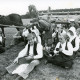ARH Slg. Bartling 4902, Bauern und Bäuerinnen in historischen Arbeitskleidern in der Ernte während einer Arbeitspause vor einem Leiterwagen sitzend, Borstel