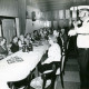ARH Slg. Bartling 4960, Altennachmittag im Wirtshaussaal, die Senioren an einem langen Tisch sitzend und schunkelnd, ein Alleinunterhalter mit Mikrofon rechts daneben stehend, Suttorf
