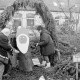 Archiv der Region Hannover, ARH Slg. Weber 02-002/0008, Personen stellen eine Baumstamm mit einem Weihnachtsmann-Gesicht unter einem Tannenbogen auf, im Hintergrund das Dorfgemeinschaftshaus, Redderse