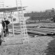 ARH Slg. Weber 02-022/0015, Bauarbeiter stehen auf einer Baustelle unter einem Baugerüst vor der Haupt- und Realschule, Gehrden