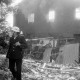 Archiv der Region Hannover, ARH Slg. Weber 02-041/0009, Ein Mitglied der Feuerwehr vor einem halb abgebrannten Haus