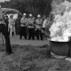 Archiv der Region Hannover, ARH Slg. Weber 02-074/0003, Ein Mitglied der Feuerwehr löscht vor weiteren Mitgliedern einen Brand bei einer Übung
